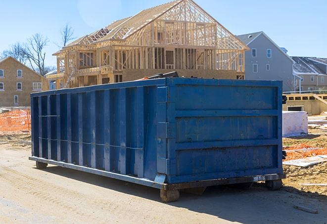 a yellow dumpster beside a construction site, with safety cones in the background